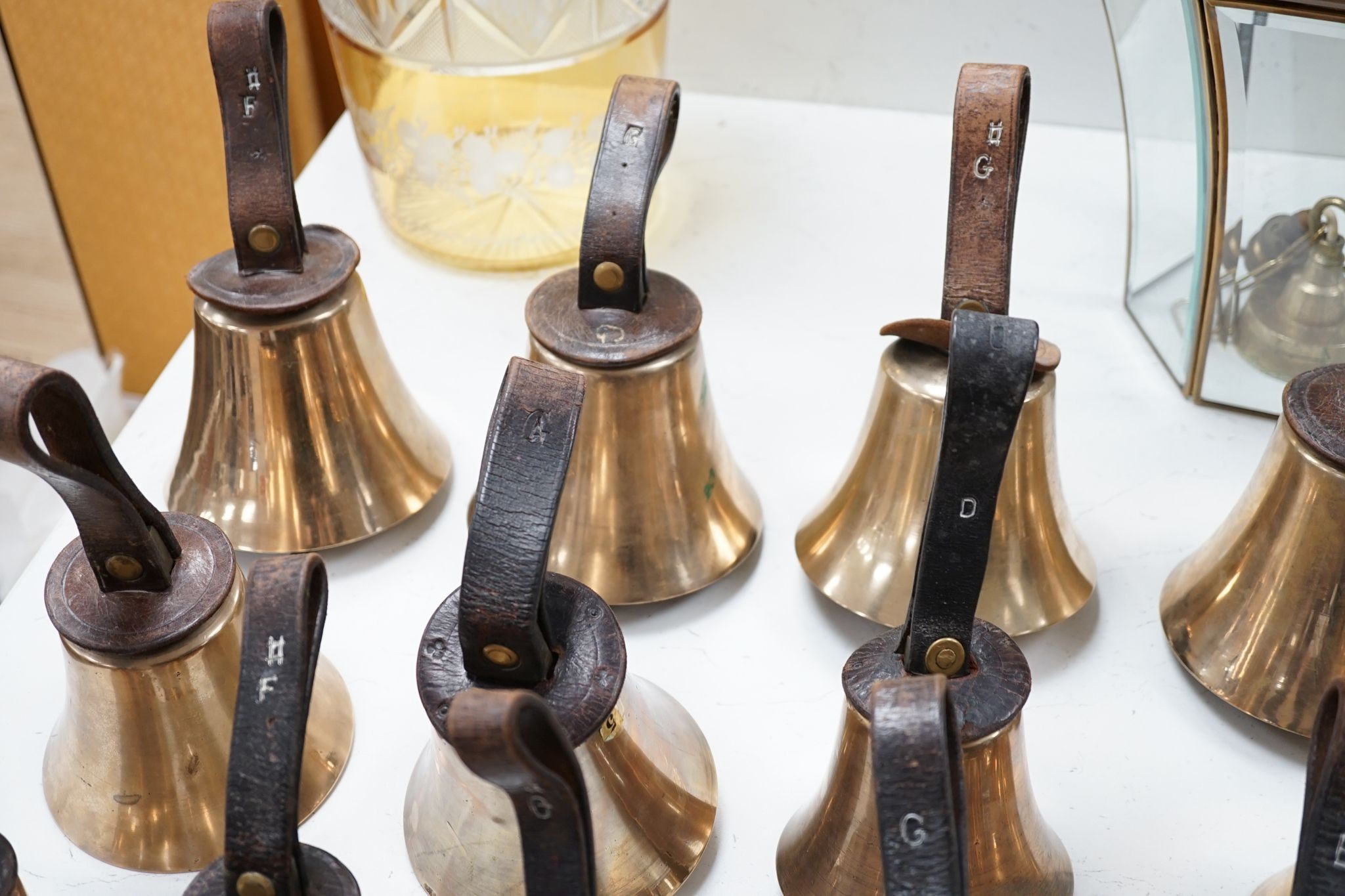 A rare set of 32 Whitechapel musical handbells, full chromatic scale, circa 1900, largest 23cm, including leather strap.